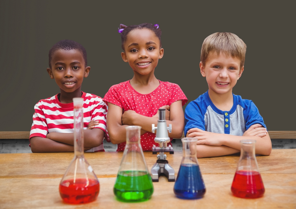 Portrait of children standing with arms crossed in chemistry lab