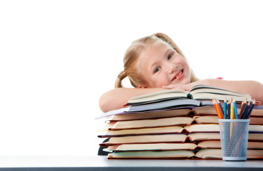 Portrait of cute schoolgirl keeping her arms on open books and looking at camera