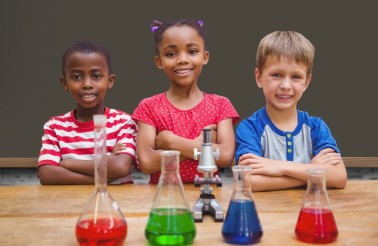 Portrait of children standing with arms crossed in chemistry lab